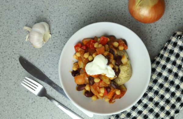 Seasoned Pioneers veggie chilli in a bowl served on a jacket potato and served with a dollop of sour cream
