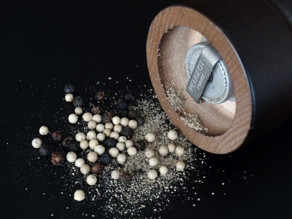 White and Black Peppercorns sitting at the bottom of grinder